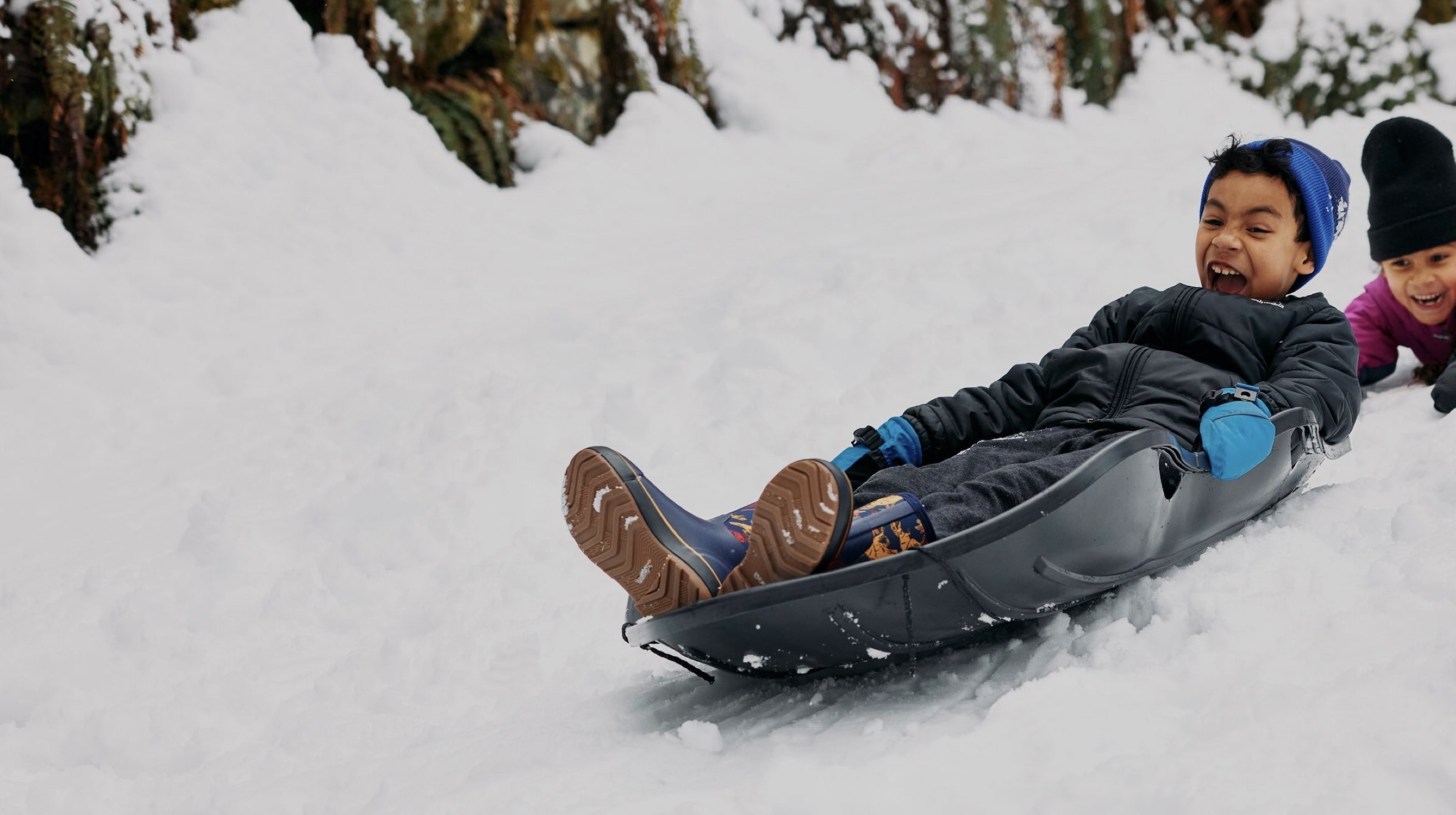 Image features the kids Classic II Dino boot on a young boy sledding.