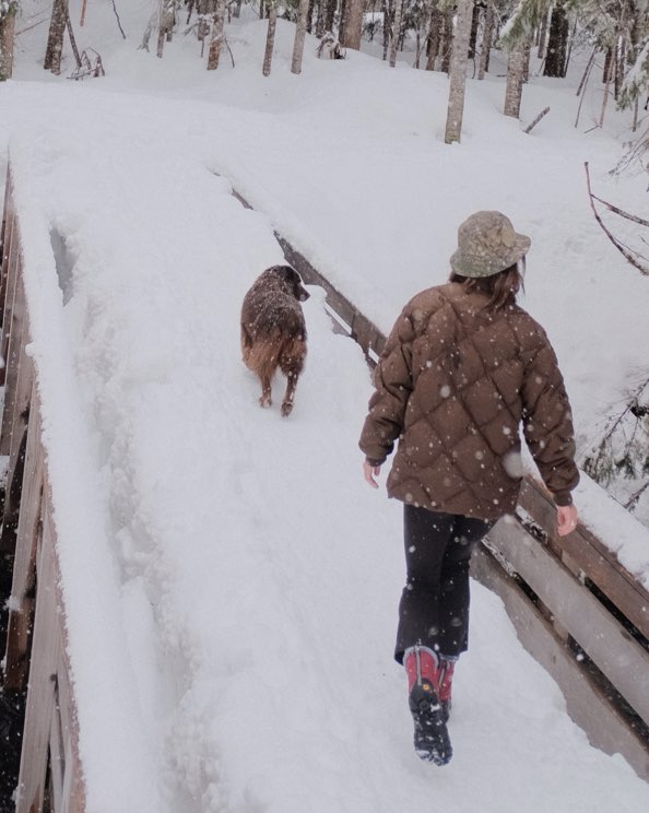 Image features the women's Cedar Quilt boot on a walk with a dog in the snow.