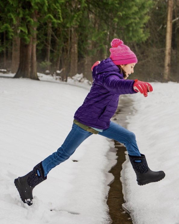 Image features the kids neo-classic boot jumping in the snow.