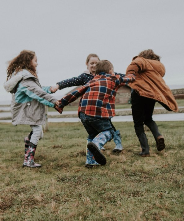 Shop our new Kids' Rainboot prints for Spring.  The image shown is a group of Kids holding hands and spinning around. Shop the variety of Kids' rainboot prints.