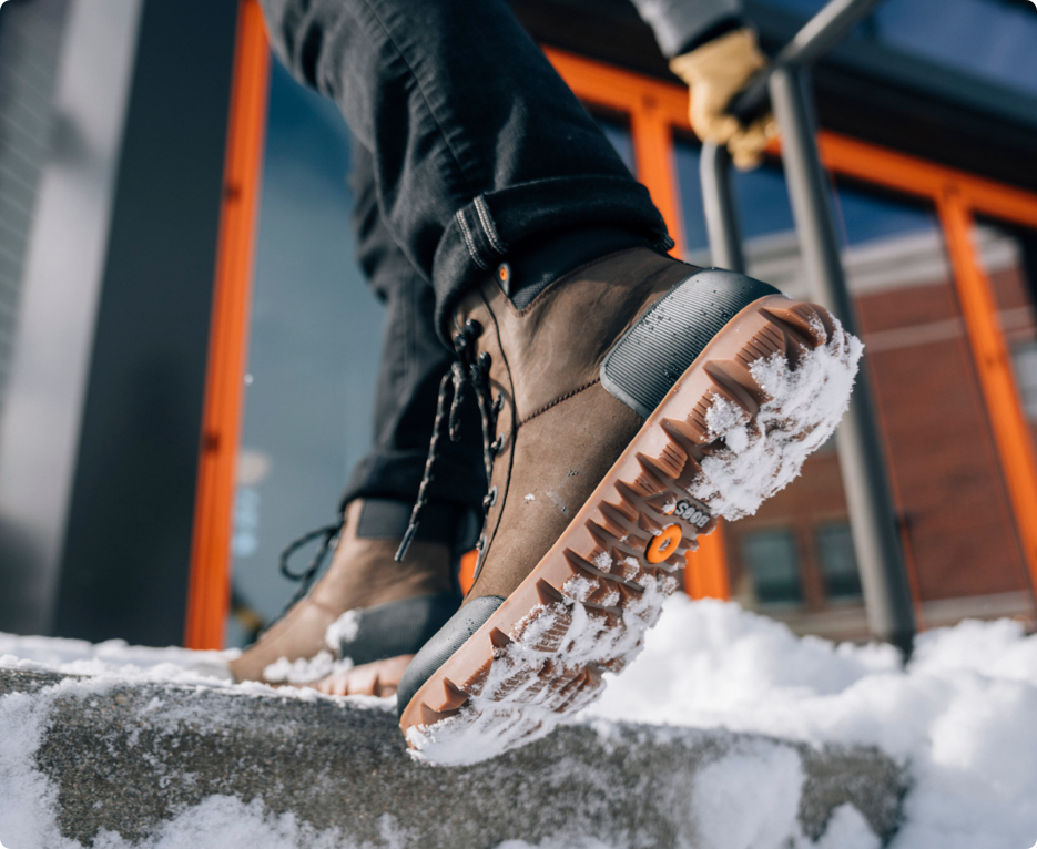 Image shown is a closeup of our Men's Arcata Urban Leather Mid waterproof boots in brown icy street backdrop. Shop now.