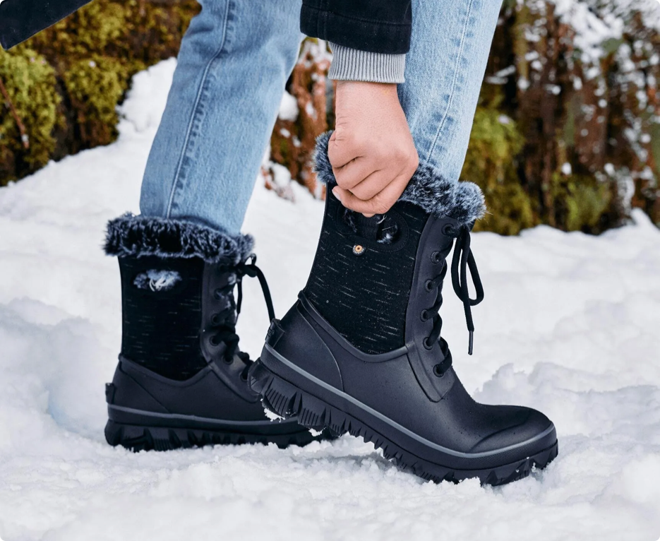 Image shown is a close-up of our Women's Arcata winter, waterproof boots in a black with faux fur lining for warmth. The backdrop is wintery snow trail.