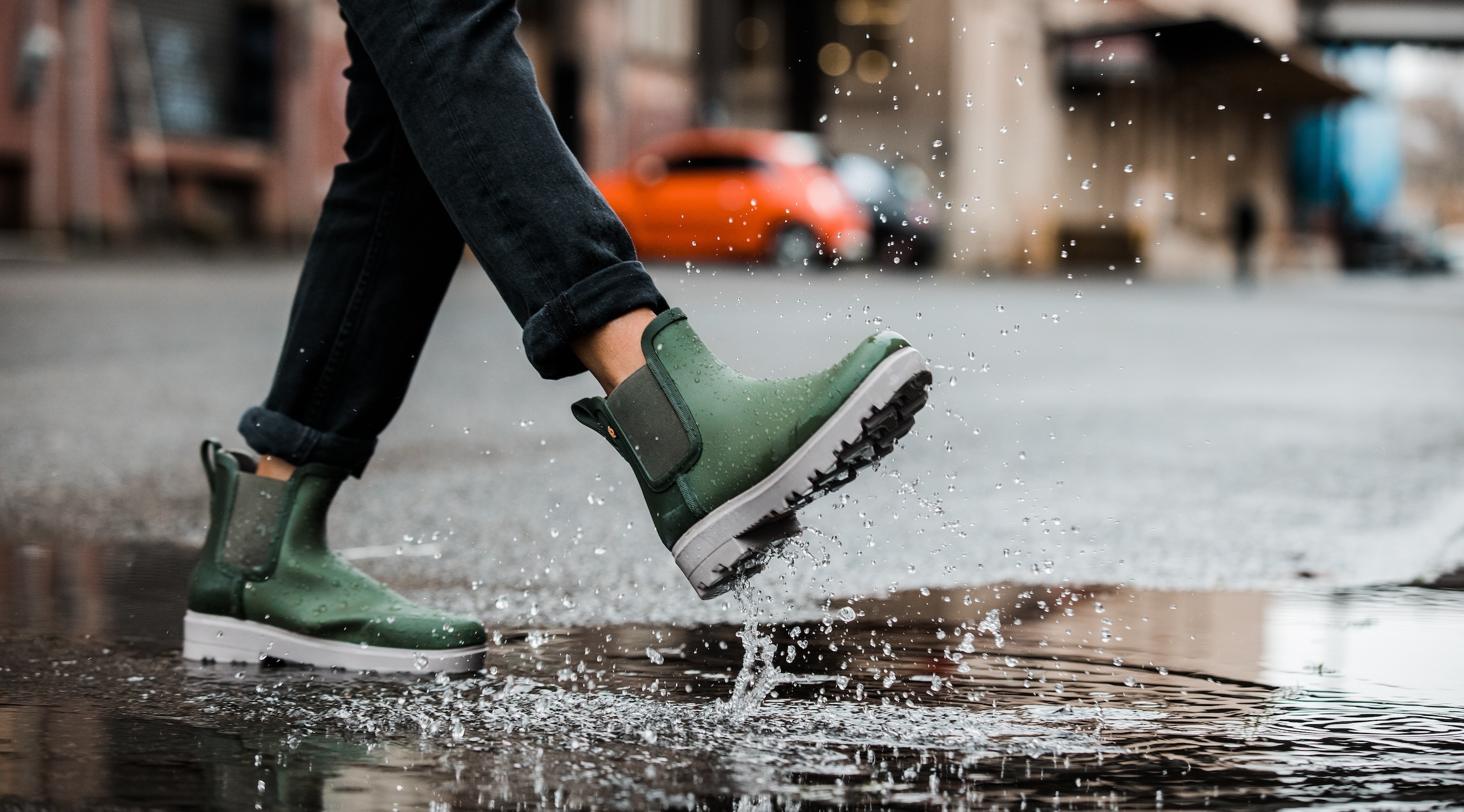 The image shown is a closeup of our women’s holly rainboot Chelsea in green splashing through a puddle.  Shop now.