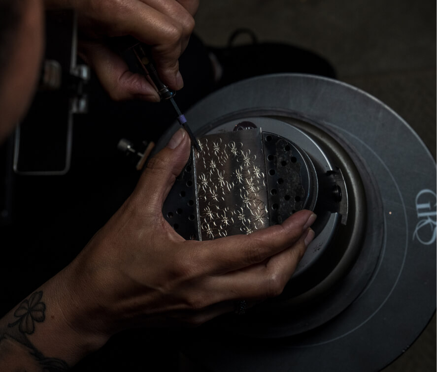 The image shown is a close up of the of Tlingit jeweler Jennifer Younger who is holding the Tlingit formline ovoid design that was originally drawn on copper.